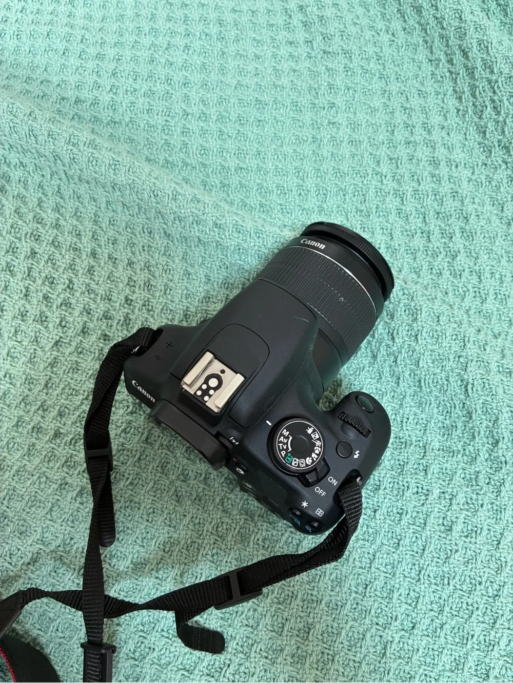 Canon DSLR Camera Body in Black with Red Strap Accents and kit lens.